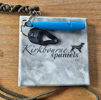 Kirkbourne Spaniels black tick puller shown alongside gundog whistle for size reference - compact PLA bioplastic straight-pull tick removal tool for keyring lanyard or game bag clip