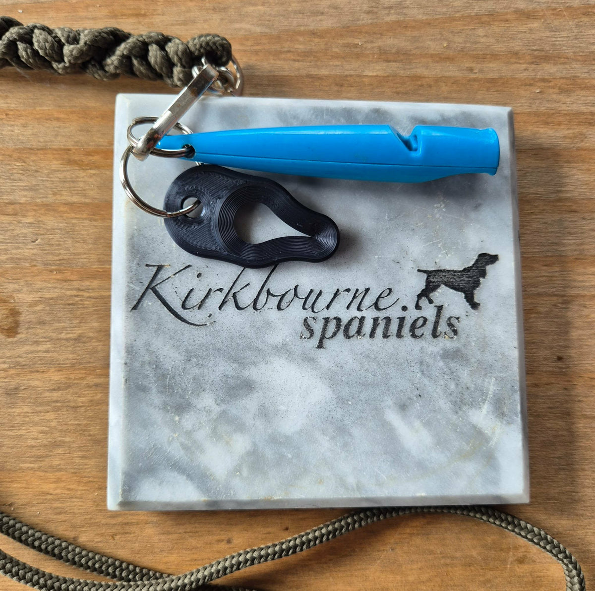 Kirkbourne Spaniels black tick puller shown alongside gundog whistle for size reference - compact PLA bioplastic straight-pull tick removal tool for keyring lanyard or game bag clip