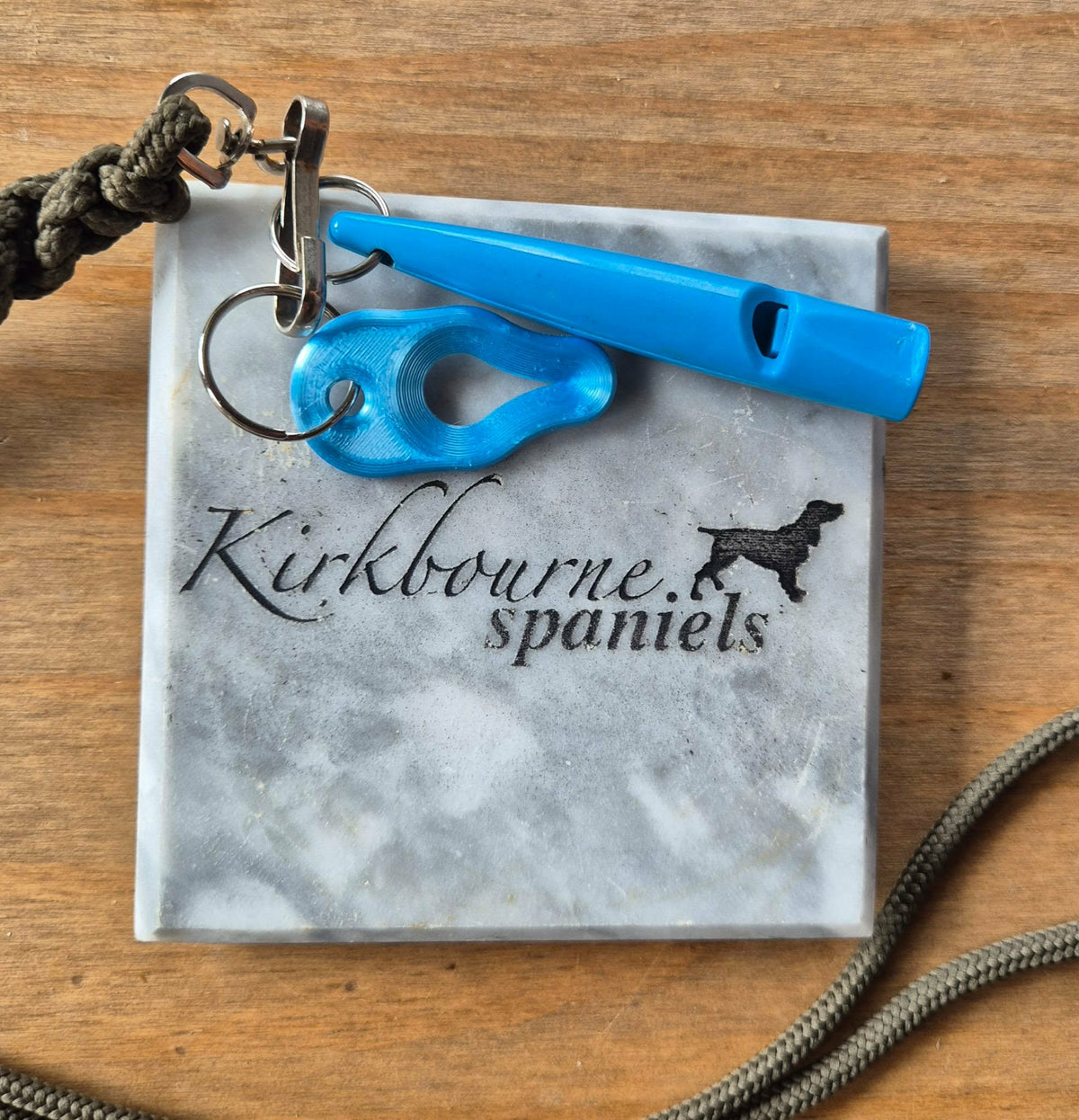 Kirkbourne Spaniels sky blue tick puller shown alongside gundog whistle for size reference - compact PLA bioplastic straight-pull tick removal tool for keyring lanyard or game bag clip